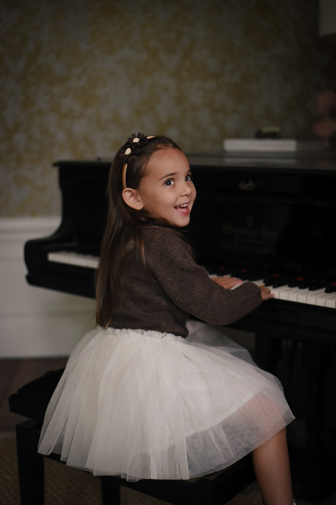 Girl wearing the Charlie Knit Cardigan in Chocolate with the Julie Tutu Skirt in White at the piano in the Canal House