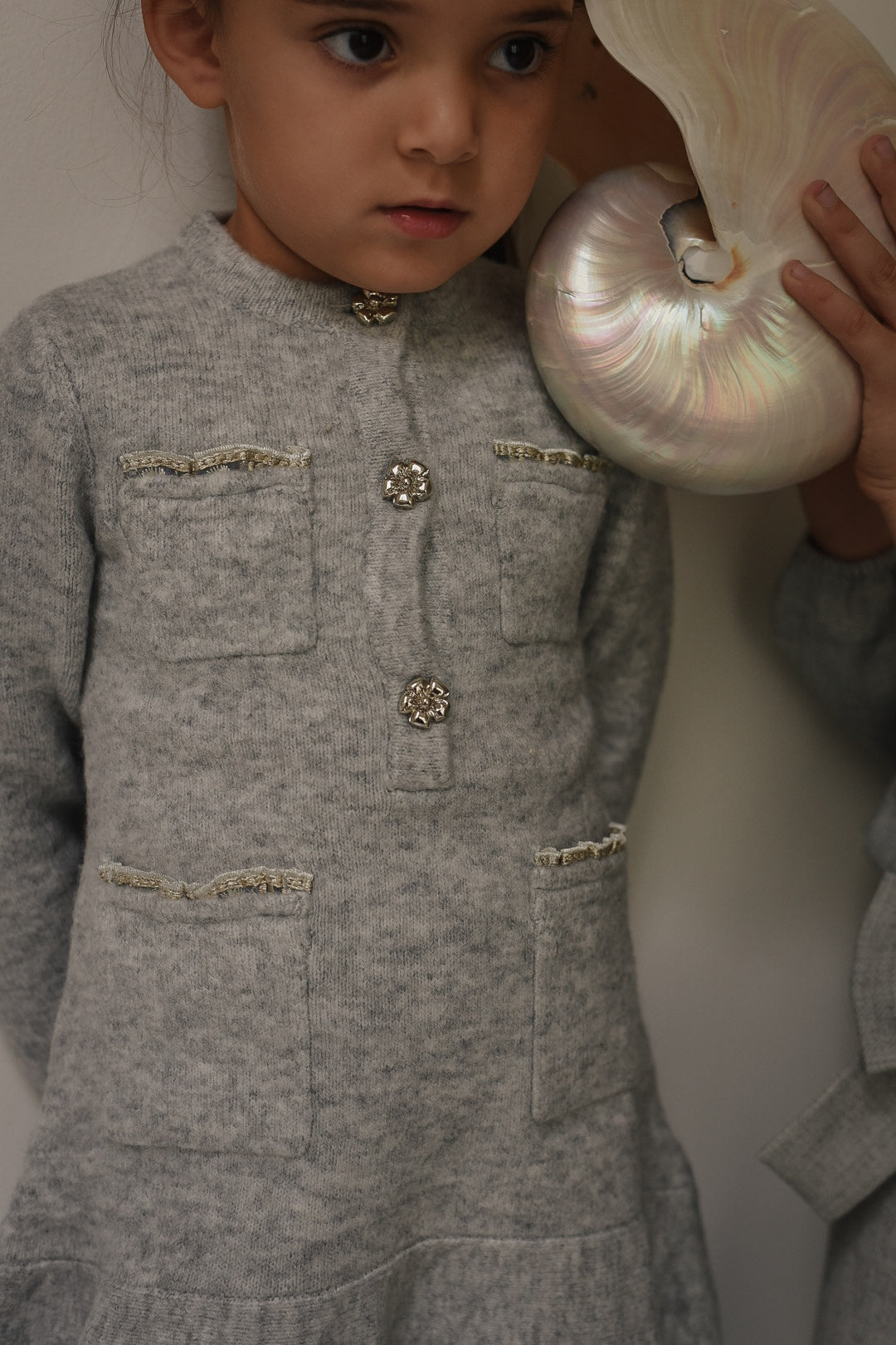 Close-up of the Charlie Knit Dress in Dove with decorative buttons and shell in the Canal House
