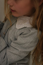 Close-up of the Elle Set in Dove showing the embroidered white collar and gold bow buttons