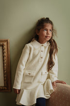 Girl wearing the Mara Tweed Dress Long Sleeve in Ivory showing the embroidered collar, gold bow buttons and tweed texture in the Canal House