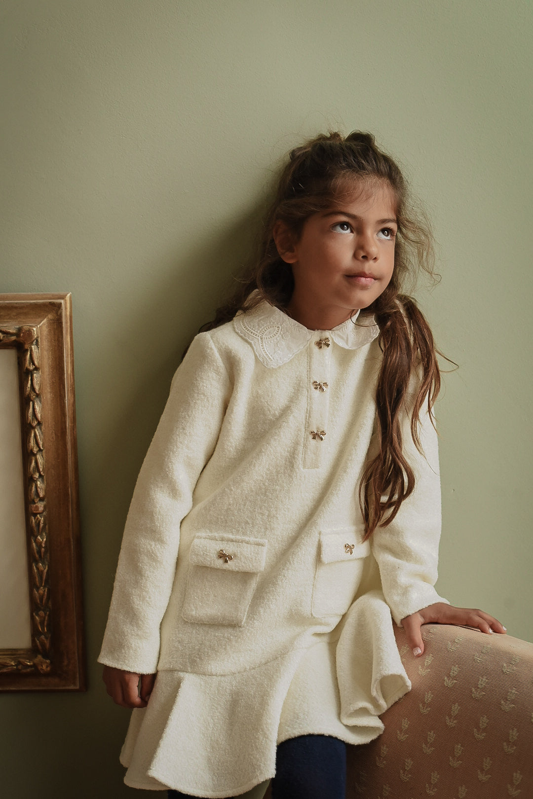 Girl wearing the Mara Tweed Dress Long Sleeve in Ivory showing the embroidered collar, gold bow buttons and tweed texture in the Canal House
