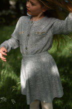 Girl wearing the Charlie Knit Dress in Dove in dappled woodland light