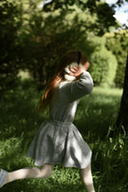 Girl wearing the Charlie Knit Dress in Dove while walking through the woodland