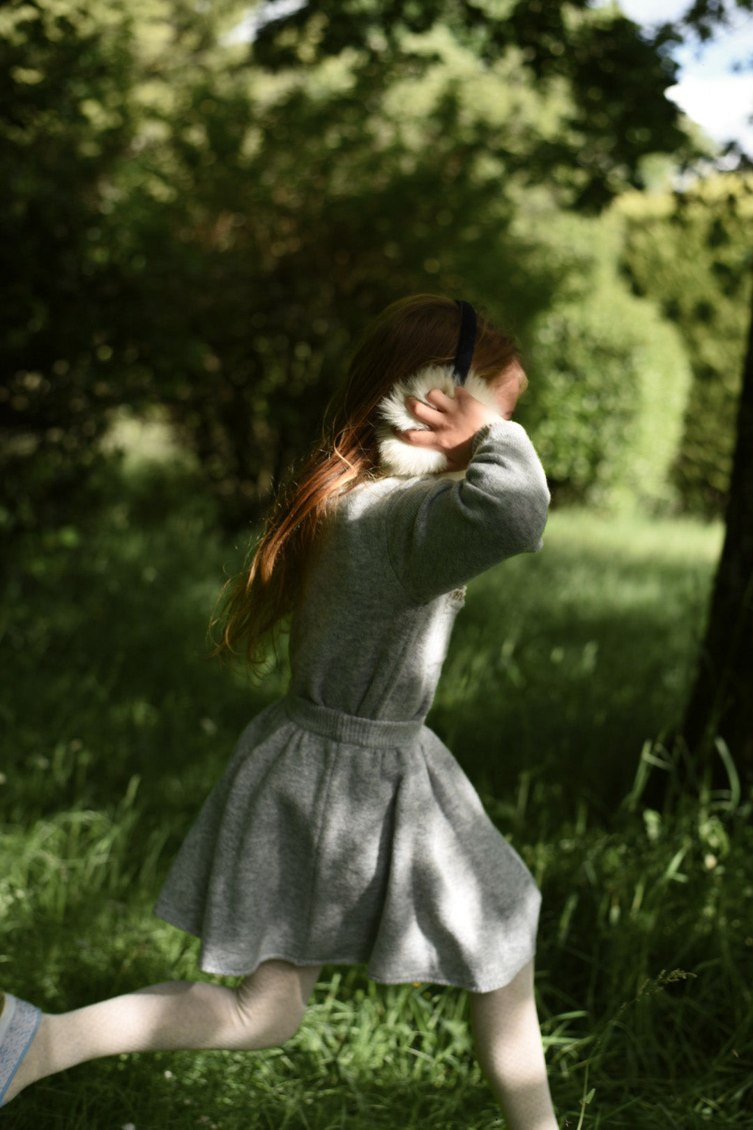 Girl wearing the Charlie Knit Dress in Dove while walking through the woodland