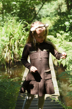 Girl wearing the chocolate Charlie Knit Dress on a woodland path