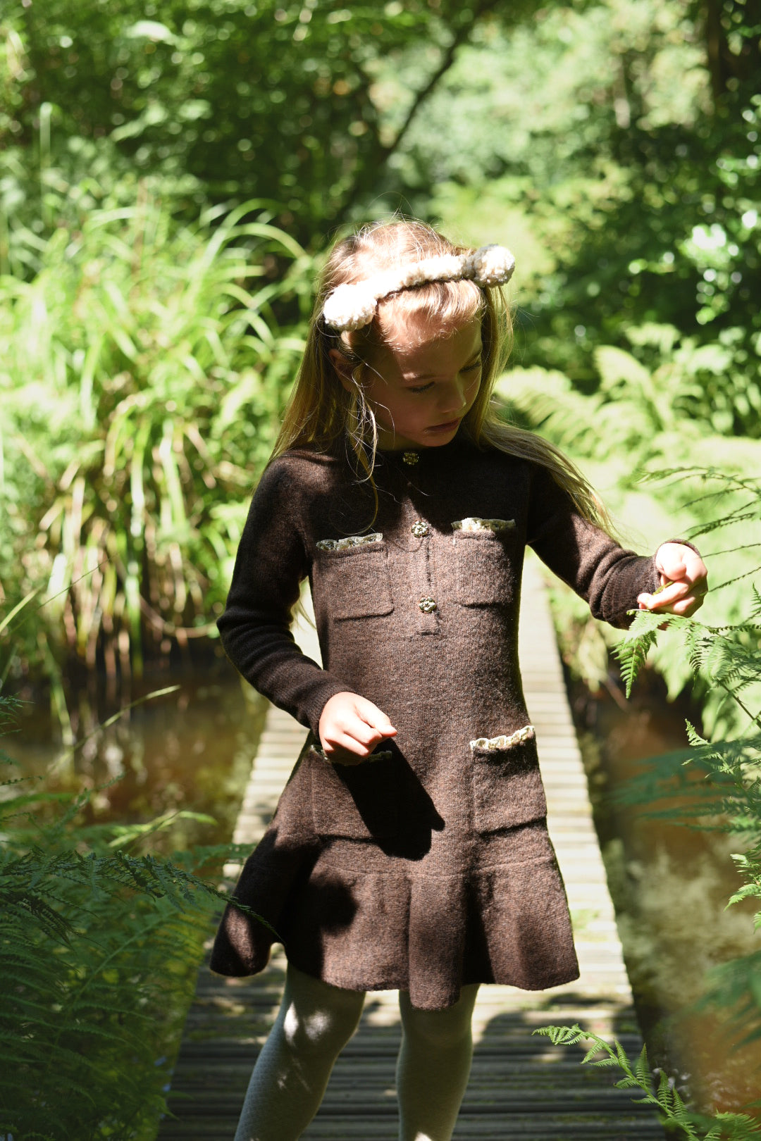 Girl wearing the chocolate Charlie Knit Dress on a woodland path