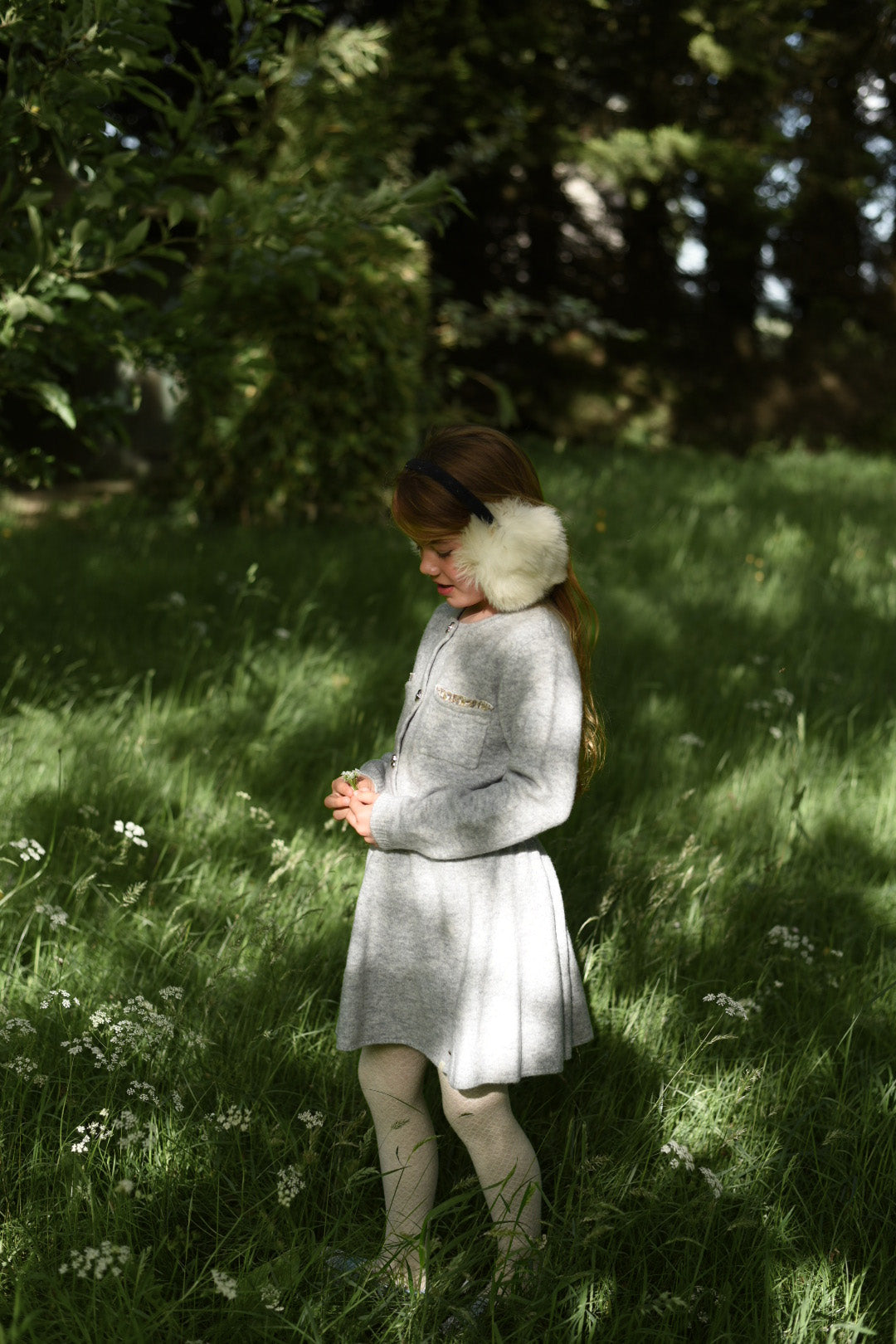 Girl wearing the dove Charlie Knit cardigan and matching skirt in the woodland