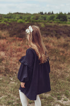 Back view of a girl wearing the Elle Dress in Navy on the heath