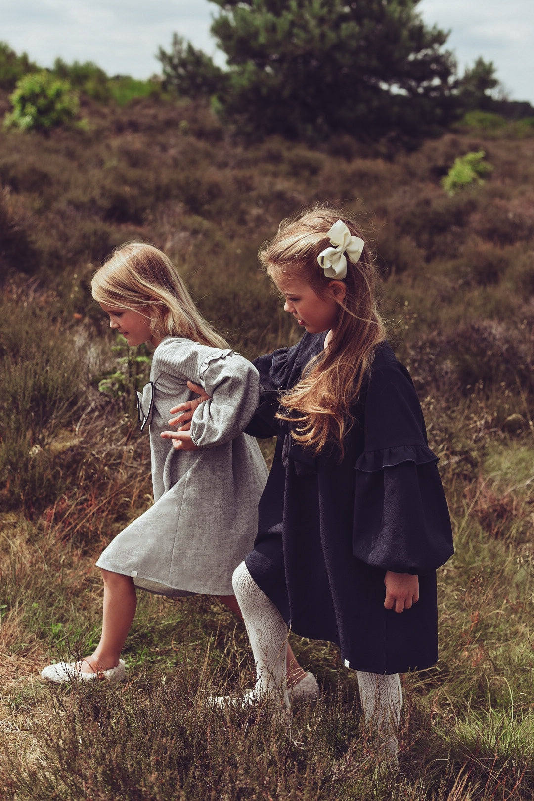 Two girls wearing the Elle Dress in dove and navy on the heath