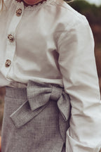 Detail of the white Valery Blouse styled with the dove Elle Skirt