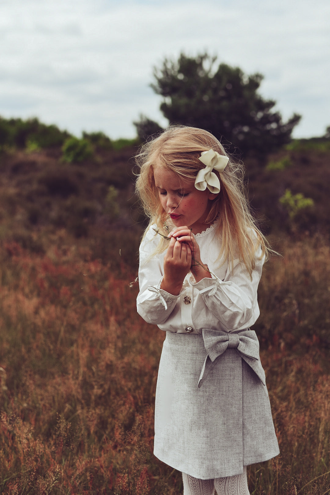Girl wearing the white Valery Blouse with the dove Elle Skirt on the heath