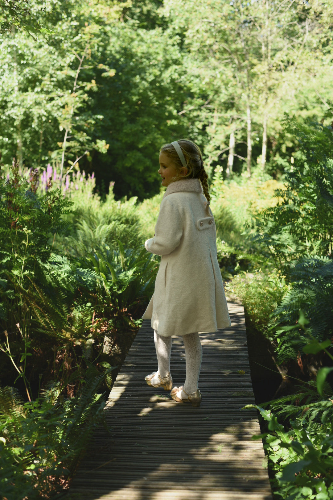 Back view of a girl wearing the Mara Tweed Coat in the woodland