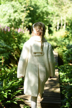 Back view of a girl wearing the Mara Tweed Coat in the woodland