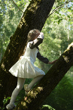Girl wearing the short-sleeve Mara Tweed Dress in the woodland