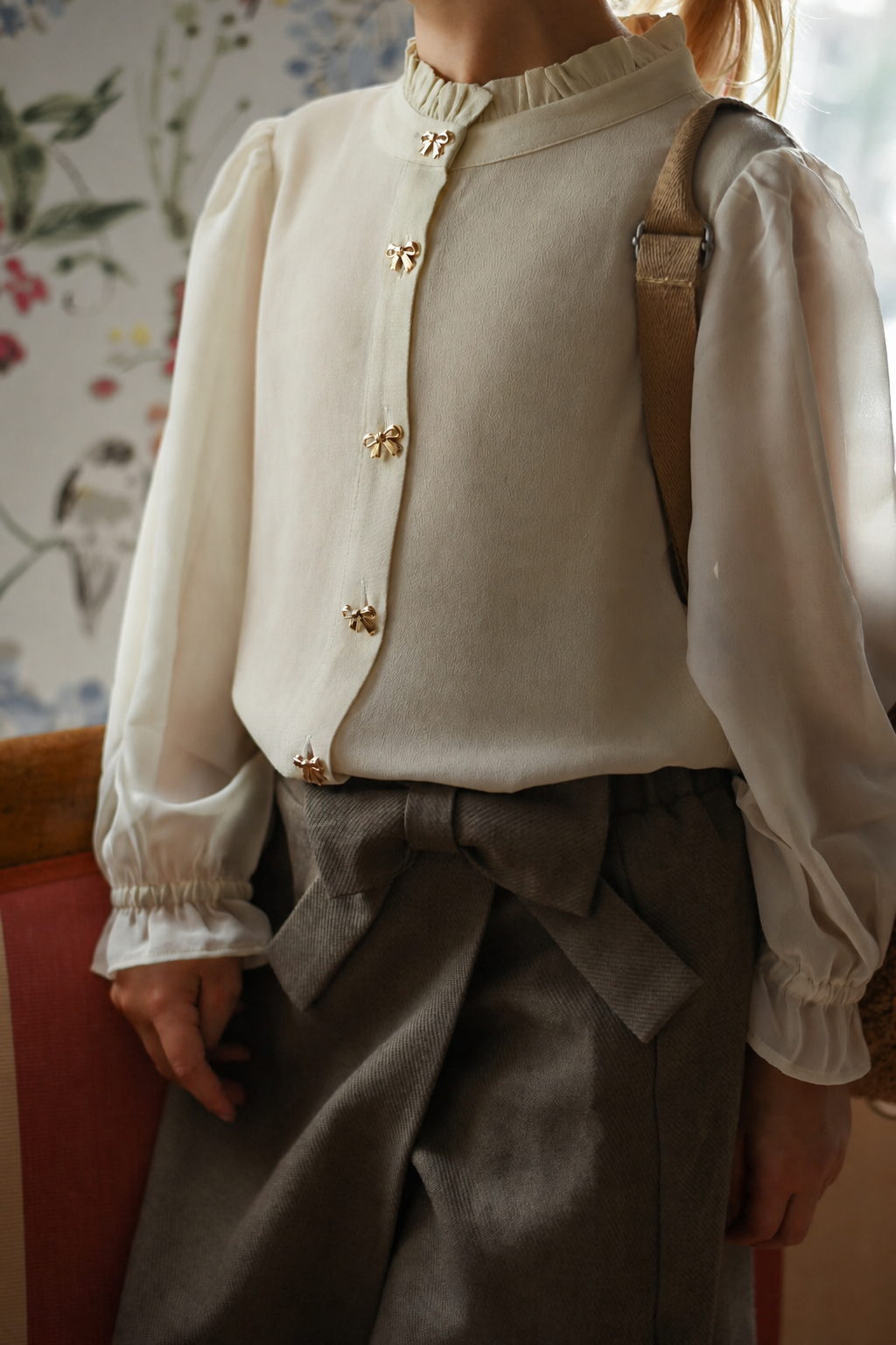Detail of the Zara Blouse Sand with bow buttons, styled with the Elle Skirt