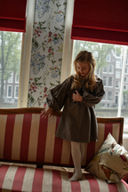 Girl wearing the Elle Dress in chocolate standing by the Canal House windows