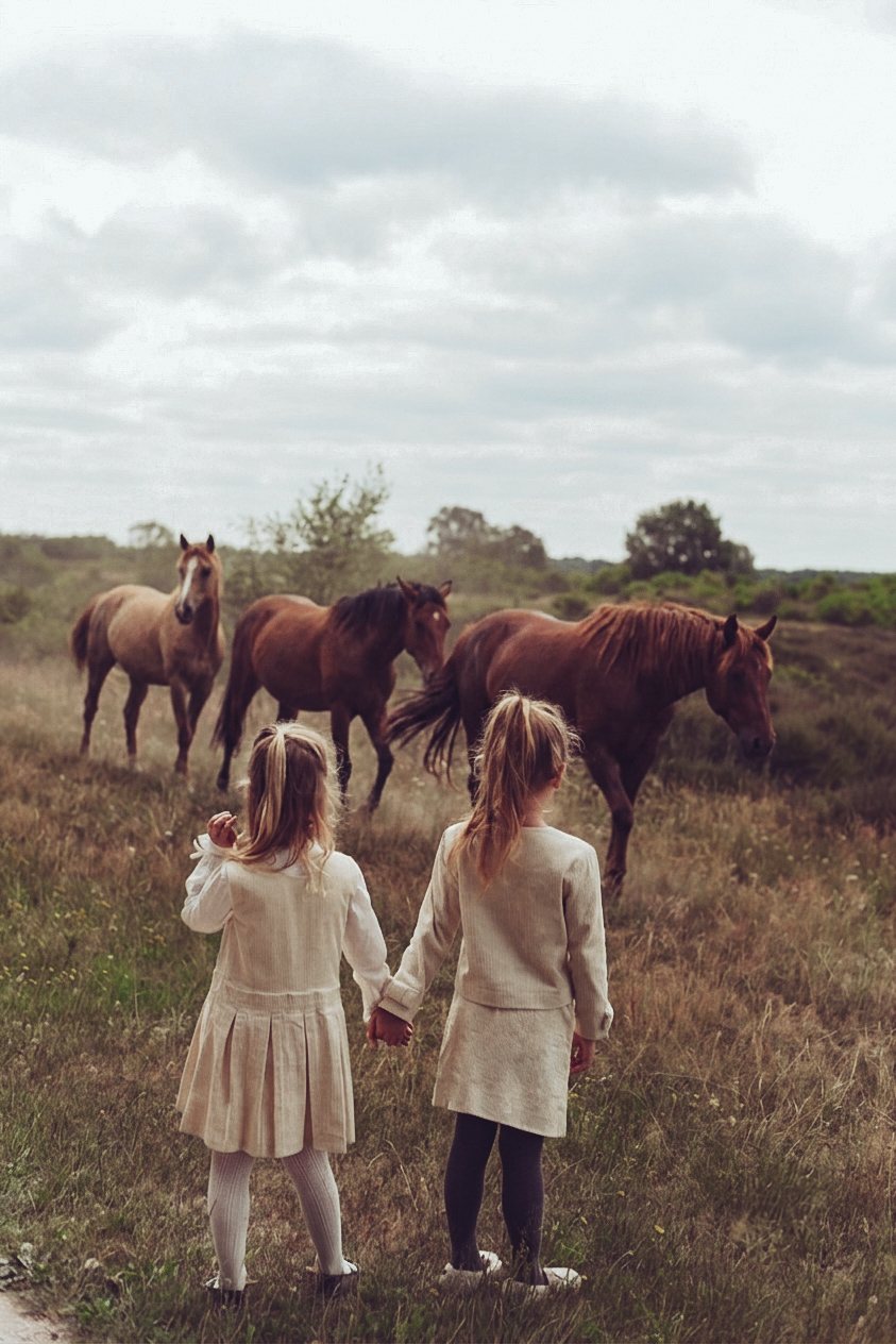 Two girls approaching horses on the heath in LRDM Petits AW26