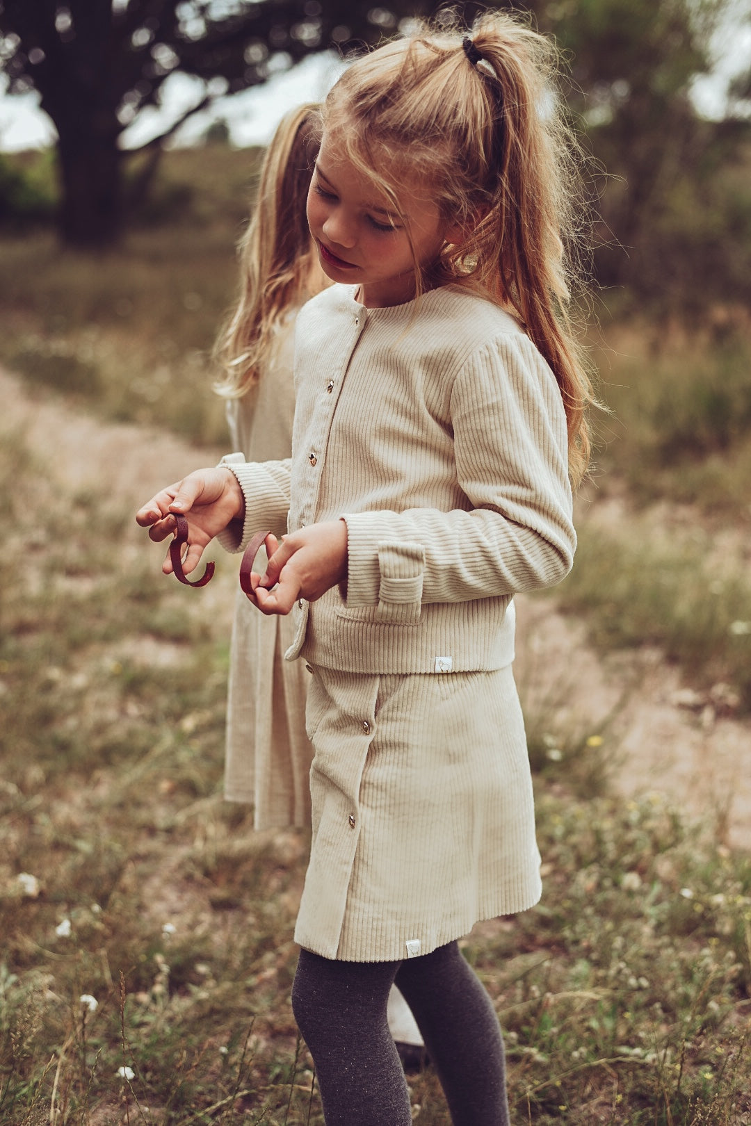 Girl wearing the Louise Rib Jacket and matching skirt in ivory on the heath