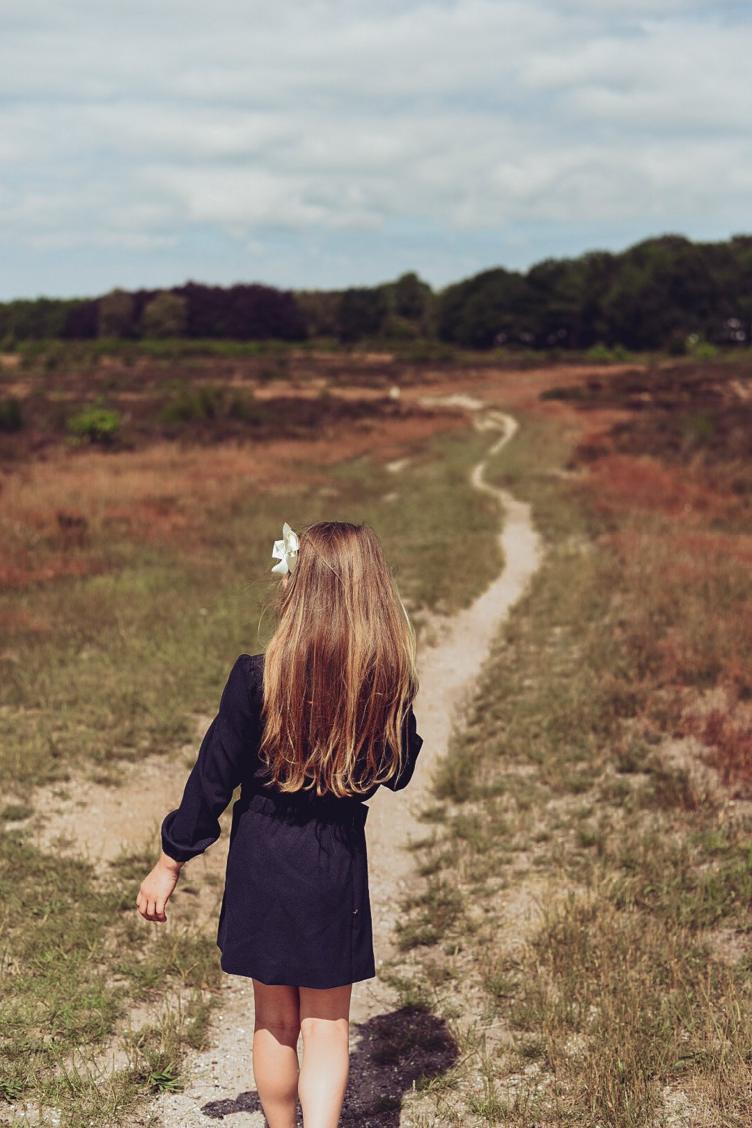 Girl seen from behind wearing the Elle Skirt in navy while walking across the heath