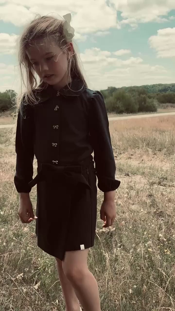 Girl wearing the Elle Blouse and matching skirt in Navy on the heath