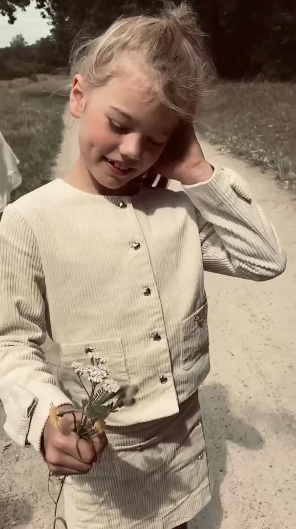 Girl wearing the Louise Jacket and matching skirt in Ivory on the heath